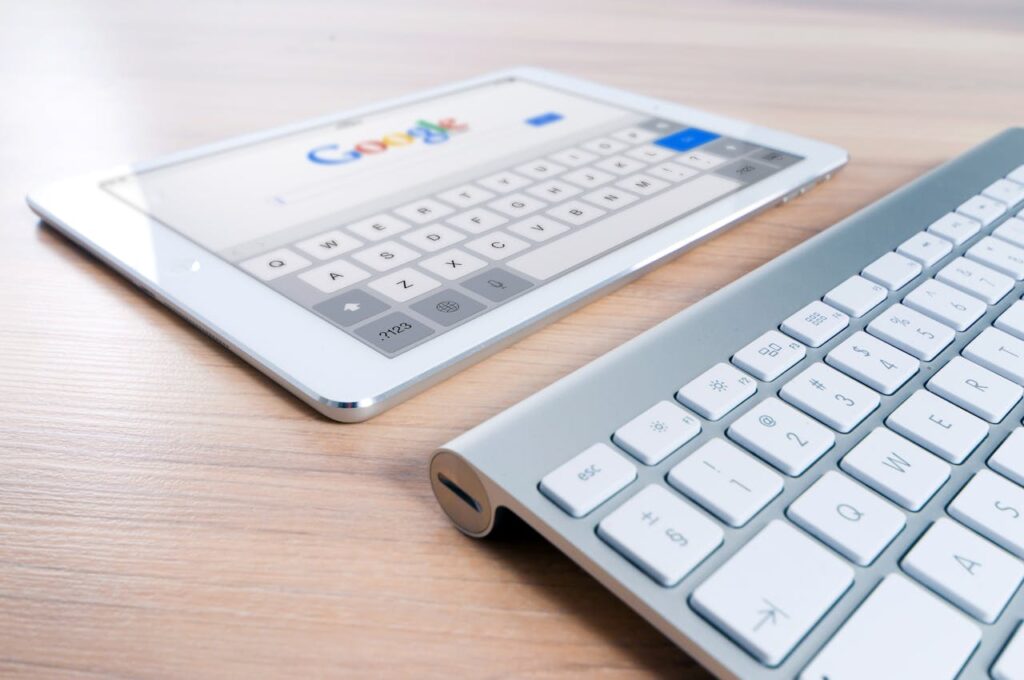 pexels-photo-270669 A modern tablet displaying a search engine logo next to a wireless keyboard on a wooden desk.