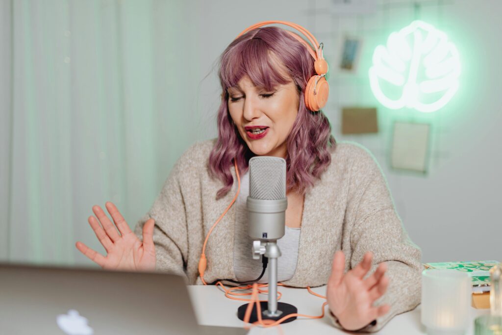 pexels-photo-6919949-6919949 Woman podcasting indoors with headphones and microphone, engaging in recording or live stream.